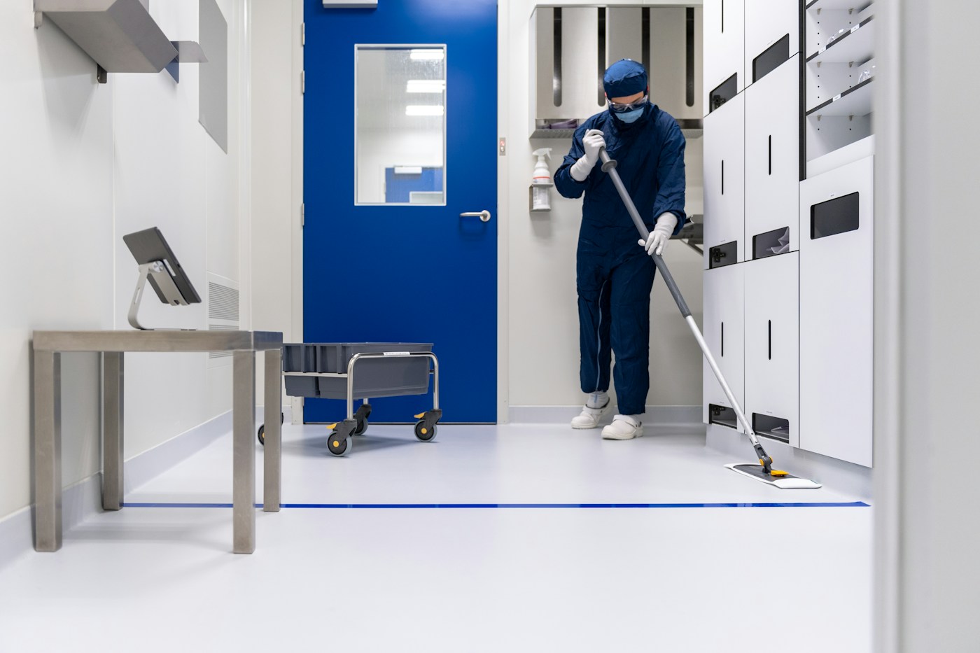 Technician in protective workwear cleaning a modern industrial facility